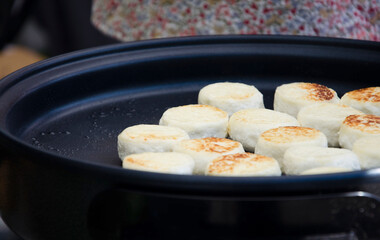 Close-up of traditional cottage cheese pancakes, known as syrniki, being cooked on a hot skillet. 