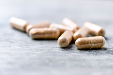 Reishi capsules. Concept for a healthy dietary supplementation. Wooden background. Soft focus. Close up.	