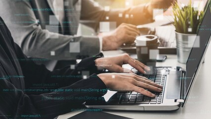 A focused business environment showcasing hands typing on a laptop with programming code and...