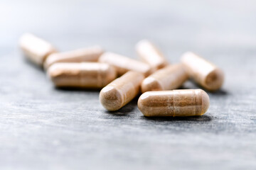 Reishi capsules. Concept for a healthy dietary supplementation. Wooden background. Soft focus. Close up.	