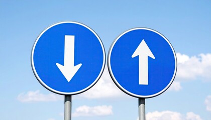 Two road signs, one with an arrow pointing down, the other with an arrow pointing up, against a clear sky