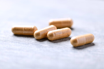 Korean Ginseng capsules. Concept for a healthy dietary supplementation. Wooden background. Soft focus. Close up.	