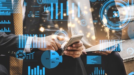 Two business professionals engage with digital data on mobile devices, surrounded by dynamic graphs...