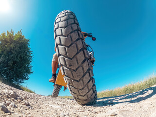 Creative photo of zoomed electric motorcycle with biker, low angle view. Arcing horizon, blue sky.