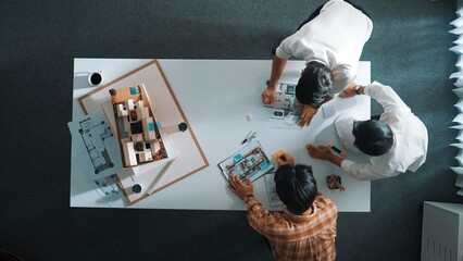 Group of skilled designer looking at model while discussing about building. Top view of architect...