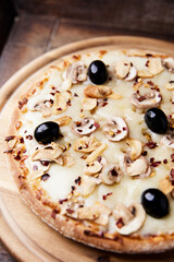 Pizza with champignons, black olives and mozzarella cheese. Wooden background. Soft focus.	