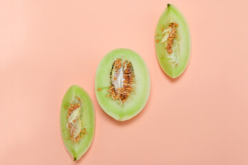 three pieces of fresh melon on a pink one flat lay