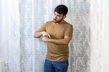 Man pointing at wrist as if checking time with serious expression