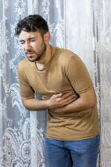 man holding stomach in pain indoors