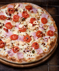 Pizza with ham, cherry tomatoes and mozzarella cheese. Wooden background. Soft focus. Close up.	