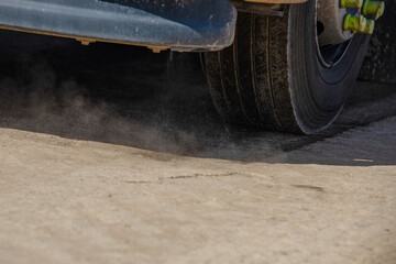 A street sweeper operates along a dirt road, using its bristles to remove dust and debris in an...