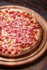 Pizza with ham and mozzarella cheese on wooden background. Soft focus. Close up	