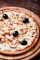 Pizza with champignons, black olives and mozzarella cheese. Wooden background. Soft focus.	