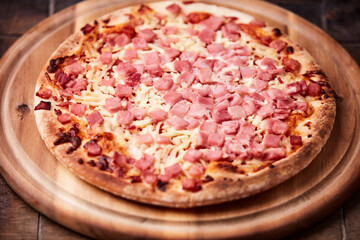 Pizza with ham and mozzarella cheese on wooden background. Soft focus. Close up	