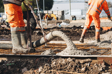 Obraz premium Close-up of Concreters builders using concrete pump to pour wet concrete at building site