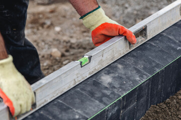 Close-up of construction worker hands  laying black stone paving blocks for landscaping at ...