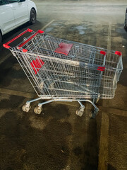 In a busy parking lot, there is a shopping cart that has been parked adjacent to a pristine white...