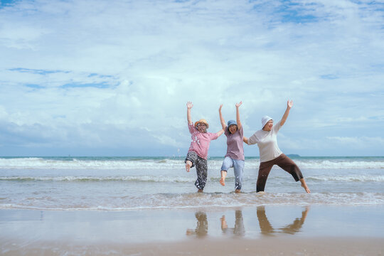 Group of three senior mature retired women on their 60s having fun enjoying together happy walking on the beach smiling playful - Powered by Adobe