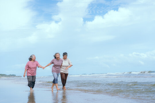 Three women enjoy a joyful walk along the beach during a sunny afternoon with gentle waves and clear blue skies