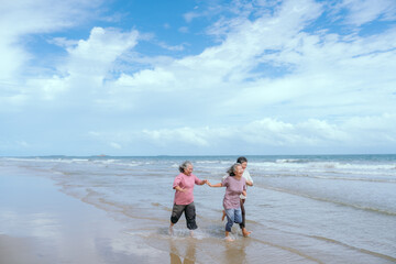 Elderly women joyfully running along the beach on a sunny day with ocean waves splashing around them