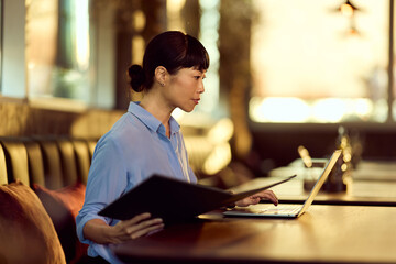 Focused Woman Using Laptop in a Modern Coffee Shop Workspace