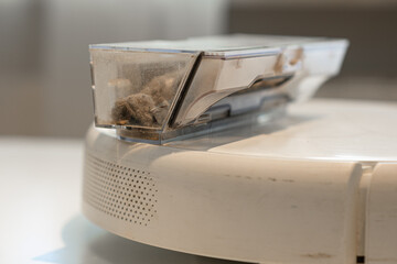 Robot Vacuum Cleaner close-up, it has a dust collection compartment filled with dust and debris....