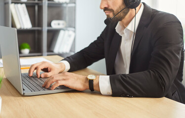 Call center operator agent sitting at the desk desk in headset working on laptop, communicating...