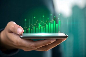 Hand holding smartphone displaying a glowing green financial growth chart with rising bars
