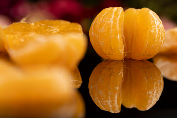 the reflection of a white orange citrus tangerine in a black mirror surface, a beautiful peeled and juicy tangerine on a black mirror