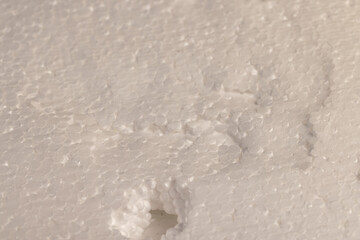 white foam for storing and transporting or building insulation, white foam made from a large number of spherical pieces joined together, closeup, dents and damages in the foam