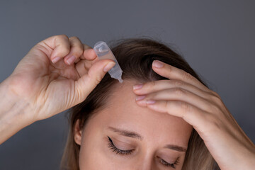 Close-up of a young woman applying nicotinic acid (vitamin B3) to the temple area for hair growth...