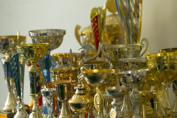 A large collection of trophies is carefully stacked on top of each other upon a sturdy table, showcasing various awards and achievements