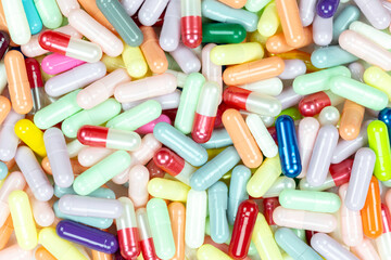 Top view of a vibrant pile of colorful medicine capsules. This pharmaceutical background represents the healthcare industry, antibiotic treatment, and the global drug market.