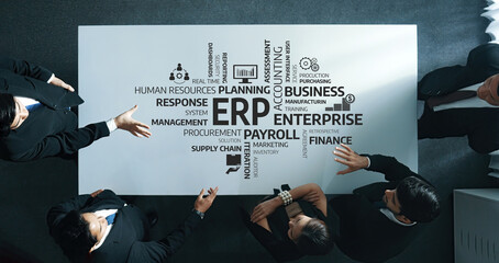 A dynamic business team collaborates over an office table with illustrative ERP concepts and keywords, enhancing strategy and planning efforts in a modern workspace. Amity