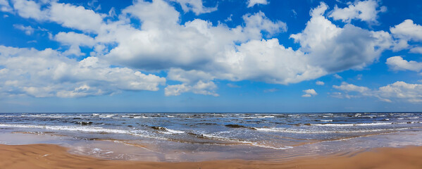Panorama of a deserted beach on the Baltic Sea with fluffy clouds in the sky in Jurmala, Latvia