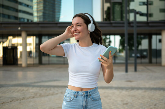 Young woman enjoying music with headphones and smartphone in urban setting
