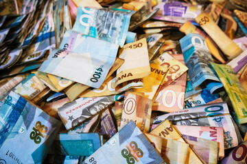 Vibrant colorful photo of mixed Ghanaian cedi notes currency money spread scattered on table desk ground floor surface background