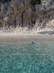 Child Swimming in Crystal Clear Water by Rocky Sardinian Coast, Cala luna