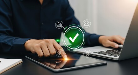 Photo of a person uses a tablet and laptop, interacting with a digital interface displaying a large green checkmark icon, symbolizing successful completion and verification of a task or process