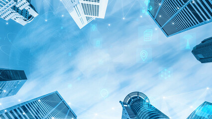 A captivating view looking up at modern skyscrapers against a clear blue sky, adorned with digital...