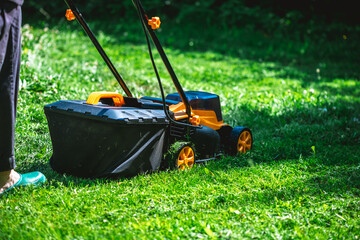 Yellow and black lawn mower cutting through fresh green grass in a vibrant garden on a sunny summer day, ensuring a beautifully maintained and healthy lawn