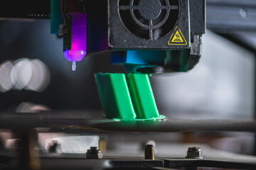 Modern 3d printer creating a green plastic object using innovative technology in a laboratory setting, showcasing the advancements in additive manufacturing