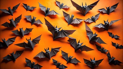 Photo of a scattering of black origami bats arranged on an orange background, creating a spooky halloween atmosphere