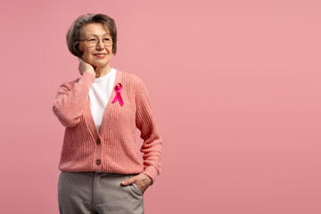 Senior woman wearing pink ribbon supporting breast cancer awareness campaign