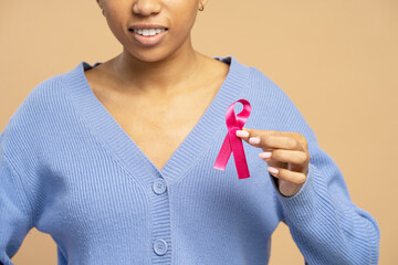 Young woman showing pink ribbon supporting breast cancer awareness