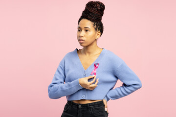 Attractive African American woman showing pink ribbon supporting breast cancer awareness campaign