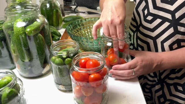 A woman prepares jars of pickled cucumbers and tomatoes, highlighting home canning, preservation, and sustainable living focus on DIY techniques