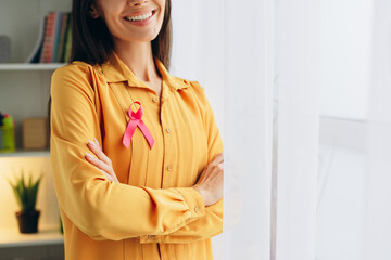 Woman smiling and wearing pink ribbon for breast cancer awareness