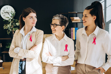 Businesswomen wearing pink ribbons showing support for breast cancer awareness
