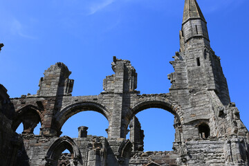 Whitby Abbey ruins against a clear blue sky. The stone structure's arches and tower are visible at Whitby Abbey - Whitby - North Yorkshire - Great Britain
